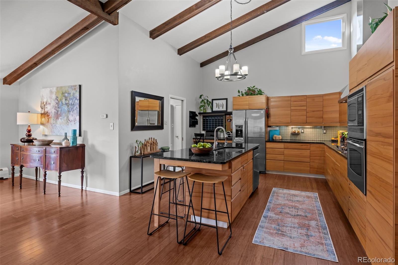1 Rangeview Drive Wheat Ridge, CO 80215 - Photo 6 of 45 a kitchen with stainless steel appliances granite countertop a refrigerator a stove top oven a dining table and chairs with wooden floor