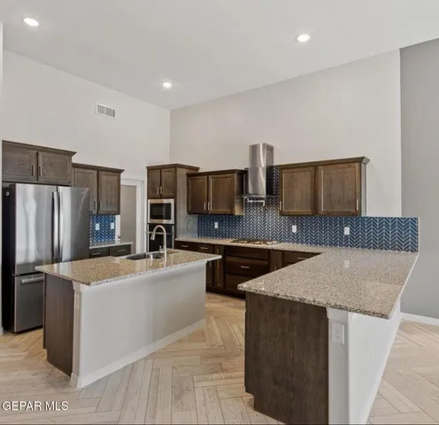 a kitchen with stainless steel appliances granite countertop a sink a stove a refrigerator a microwave oven with white cabinets