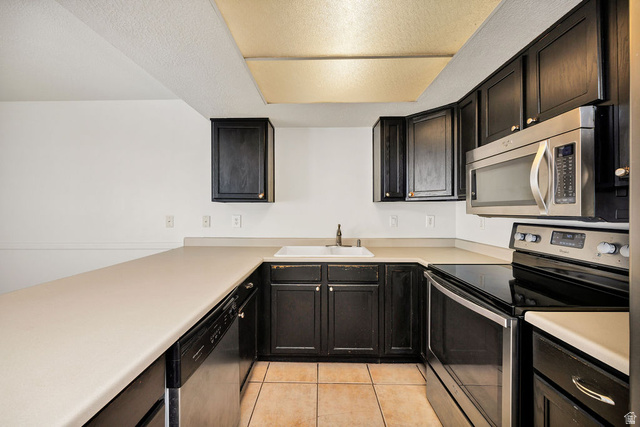 2 West 1780 North Logan, UT 84341 - Photo 4 of 24 Kitchen featuring stainless steel appliances, light countertops, a textured ceiling, dark cabinets, and light tile patterned flooring