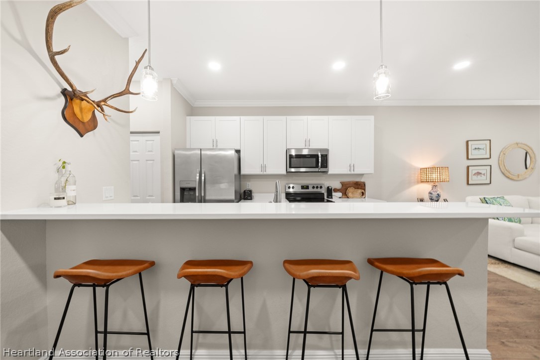 4734 Haw Branch Road, Unit 110 Sebring, FL 33875 - Photo 10 of 50 a kitchen with stools a sink and a stove with chairs