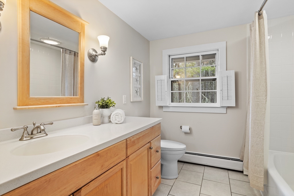 103 Newtown Road Acton, MA 01720 - Photo 25 of 42 a bathroom with a granite countertop sink a toilet and a window