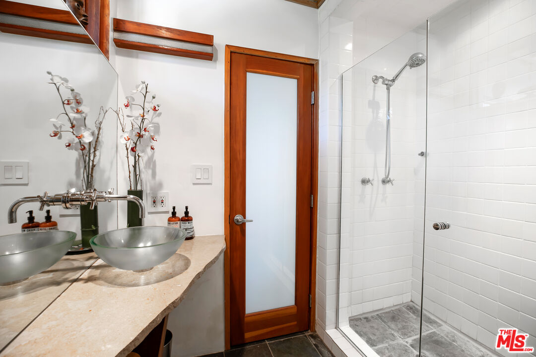 14840 Sunset Boulevard Pacific Palisades, CA 90272 - Photo 21 of 33 a bathroom with a granite countertop sink and a shower