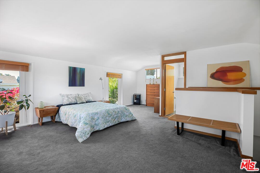 14840 Sunset Boulevard Pacific Palisades, CA 90272 - Photo 22 of 33 a spacious bedroom with a bed and a chandelier