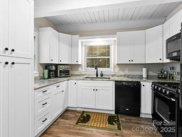 a kitchen with stainless steel appliances granite countertop a stove a sink and a white cabinets