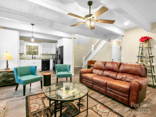 a living room with furniture kitchen view and a chandelier