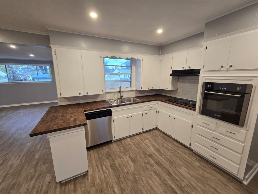 233 Roma Drive Shreveport, LA 71105 - Photo 2 of 12 Kitchen featuring wall oven, a peninsula, dark wood-type flooring, stainless steel dishwasher, and ornamental molding