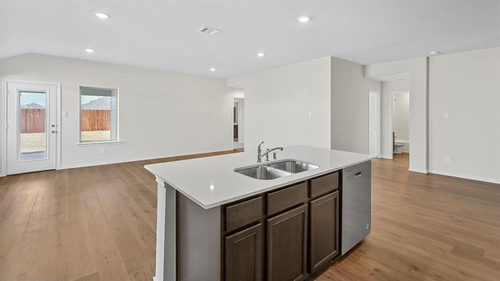 1953 Freeman Street Tyler, TX 75704 - Photo 5 of 32 Kitchen island featuring a dual-basin stainless steel sink, contemporary faucet, dark wood-finish cabinetry, and a dishwasher appliance