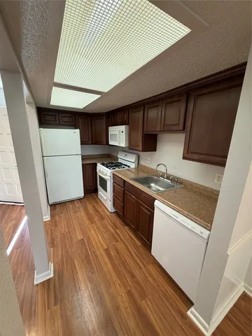 a kitchen with wooden floors and white stainless steel appliances