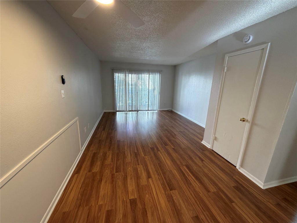 1725 Toomey Road Austin, TX 78704 - Photo 7 of 11 Spare room featuring a textured ceiling, dark wood-style floors, and ceiling fan