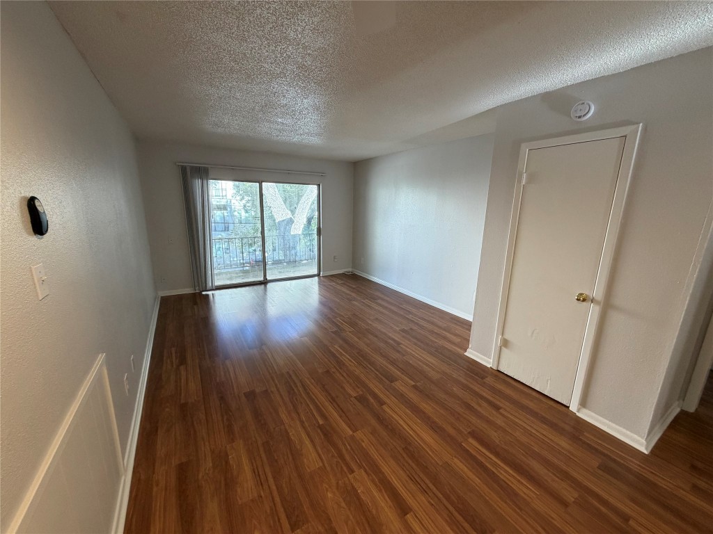 1725 Toomey Road Austin, TX 78704 - Photo 8 of 11 Spare room featuring dark wood-style flooring and a textured ceiling