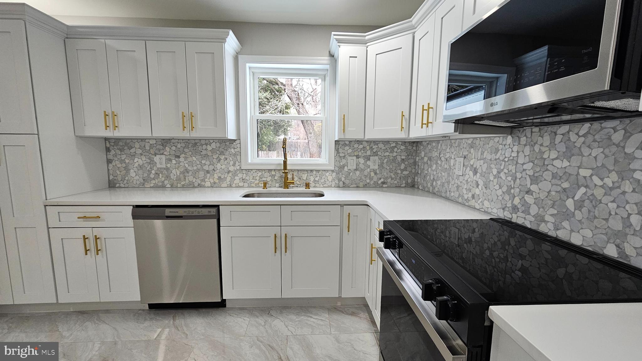 1305 Woodside Parkway Silver Spring, MD 20910 - Photo 7 of 41 a kitchen with white cabinets a sink dishwasher and a stove with wooden floor