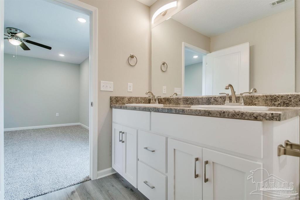 5601 Riviera Drive Milton, FL 32583 - Photo 16 of 18 a bathroom with a granite countertop sink and a mirror