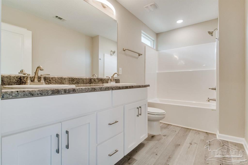5601 Riviera Drive Milton, FL 32583 - Photo 17 of 18 a bathroom with a double vanity sink toilet mirror and bathtub