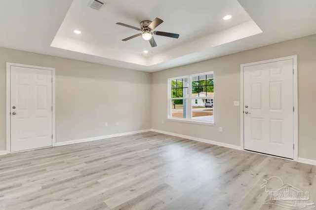 an empty room with wooden floor ceiling fan and windows