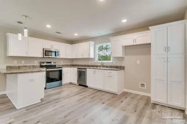 a kitchen with granite countertop white cabinets and stainless steel appliances