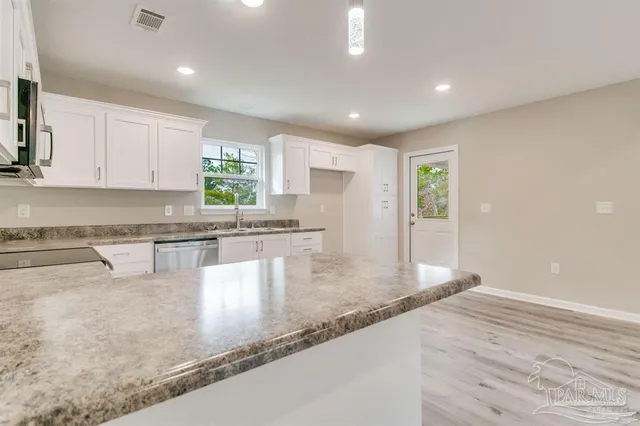 a kitchen with granite countertop a stove a sink and a counter top space