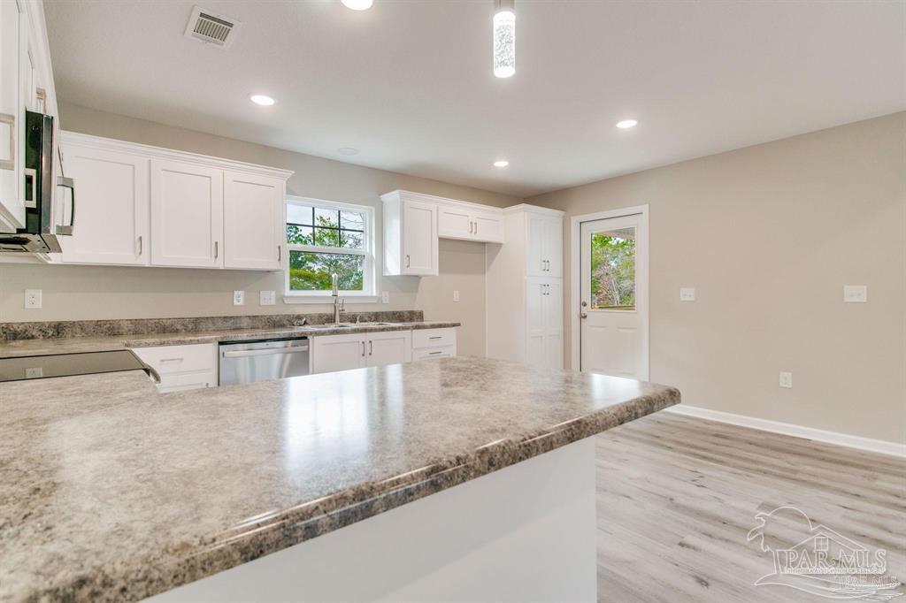 5601 Riviera Drive Milton, FL 32583 - Photo 7 of 18 a kitchen with granite countertop a stove a sink and a counter top space