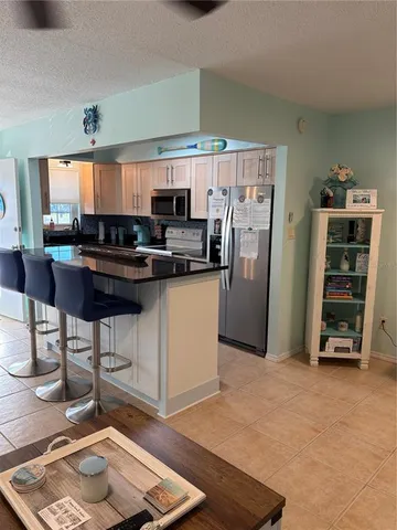 a kitchen with stainless steel appliances a stove a refrigerator a sink a dining table and chairs with wooden floor