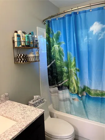 a bathroom with a granite countertop sink and a toilet