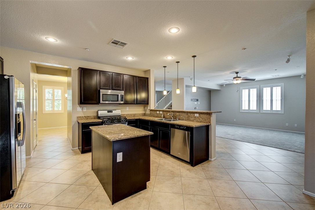 3199 Subtle Color Avenue Henderson, NV 89044 - Photo 45 of 46 Kitchen featuring open floor plan, hanging light fixtures, stainless steel appliances, a peninsula, and dark wood finish cabinetry