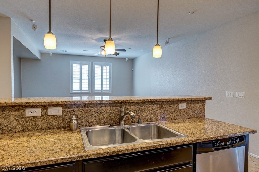 3199 Subtle Color Avenue Henderson, NV 89044 - Photo 18 of 46 Kitchen featuring stainless steel dishwasher, light stone countertops, ceiling fan, and pendant lighting