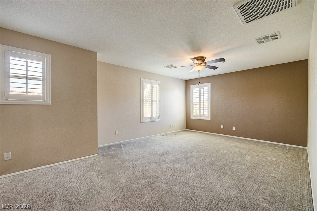 3199 Subtle Color Avenue Henderson, NV 89044 - Photo 22 of 46 Spare room with a ceiling fan, light colored carpet, and a textured ceiling