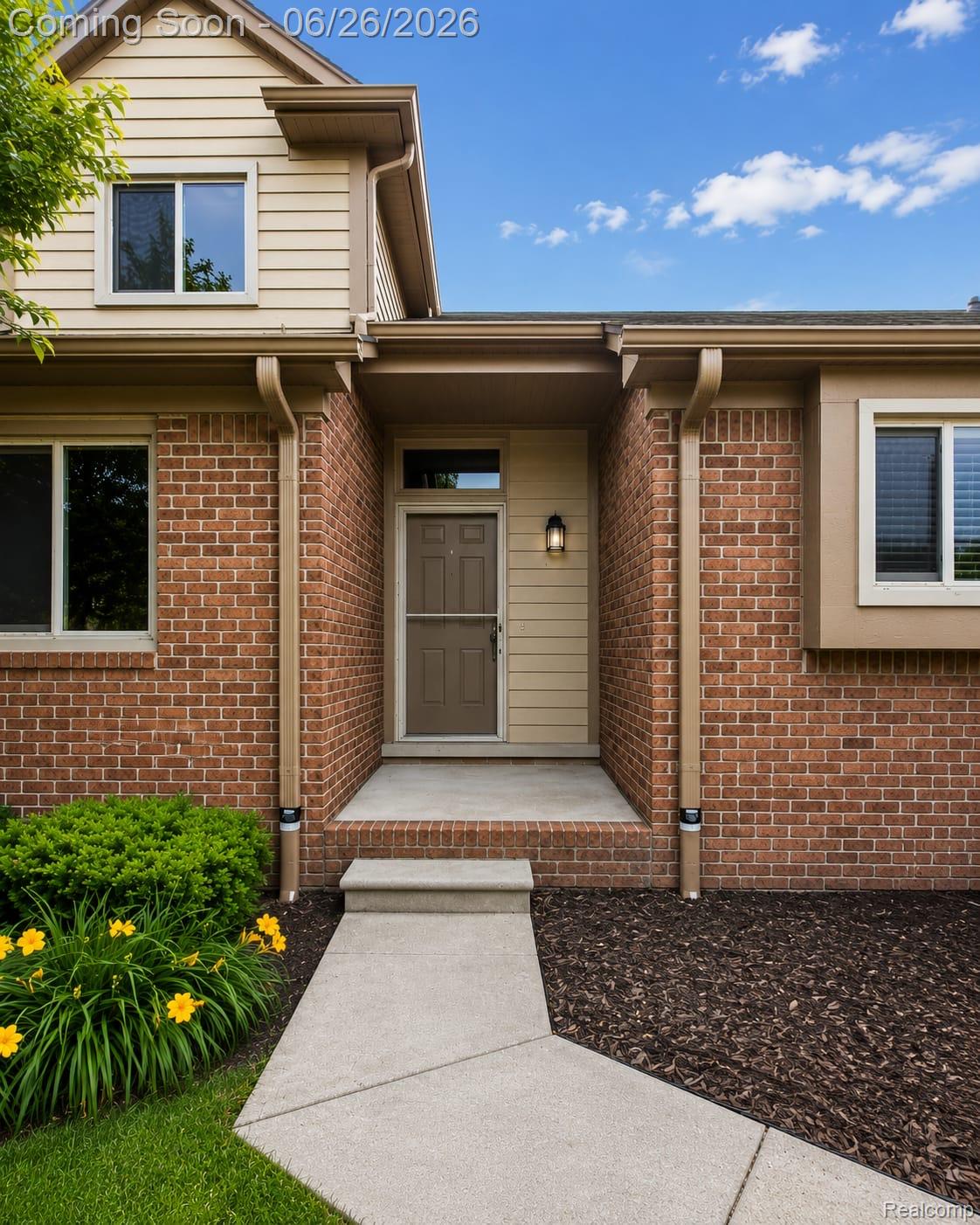 17014 Country Ridge Lane Macomb, MI 48044 - Photo 2 of 25 Brick and siding exterior featuring a concrete walkway, mature landscaping, and an inviting entryway with an exterior light fixture