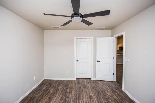 a view of room with hardwood floor and a ceiling fan