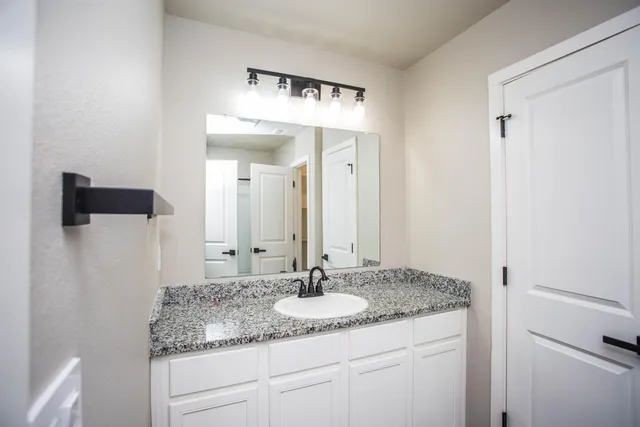 a bathroom with a granite countertop sink and a mirror