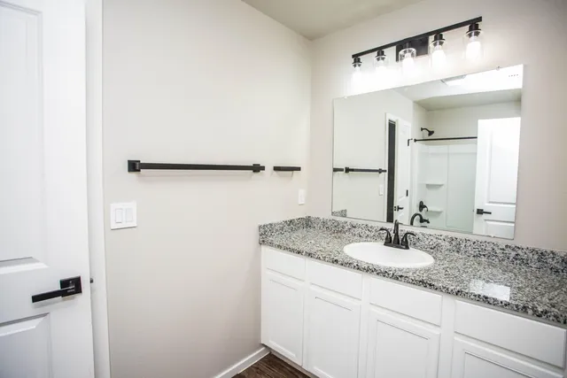 a bathroom with a granite countertop sink and a mirror
