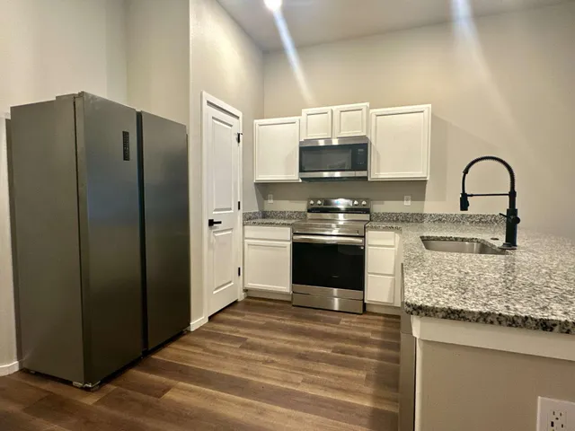 a kitchen with stainless steel appliances granite countertop a stove a sink and a refrigerator