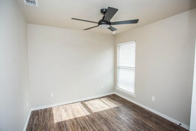 a view of empty room with wooden floor and fan