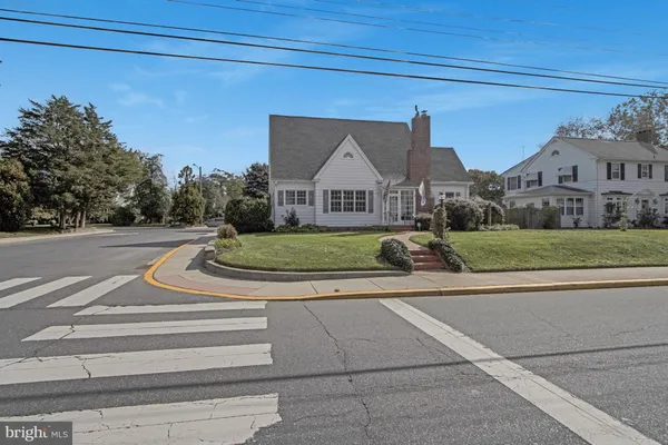 a view of a house next to a big yard and large trees
