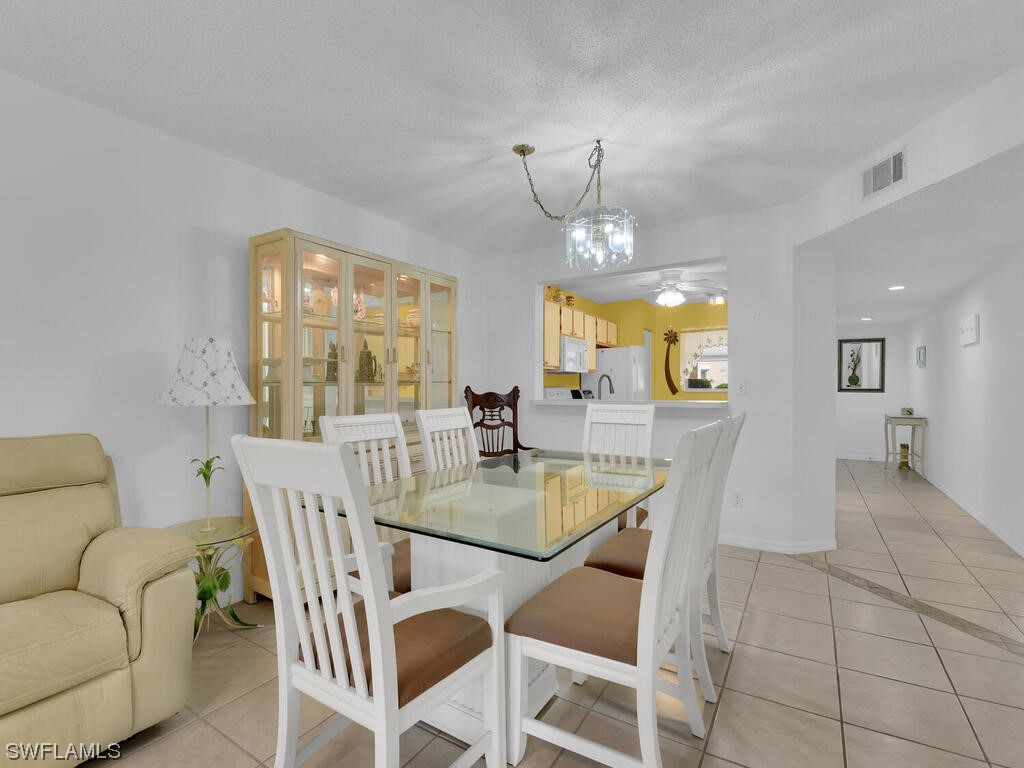 654 Squire Circle, Unit 103 Naples, FL 34104 - Photo 11 of 23 a view of a dining room with furniture and wooden floor