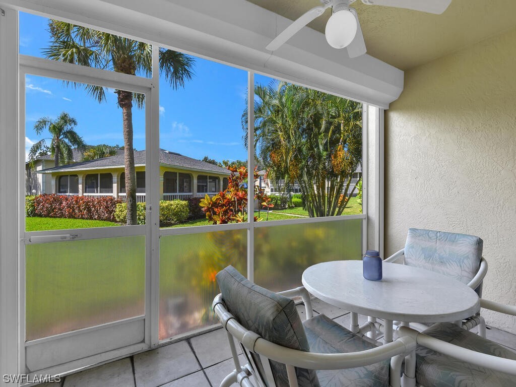 654 Squire Circle, Unit 103 Naples, FL 34104 - Photo 4 of 23 a view of a patio with table and chairs potted plants with wooden floor