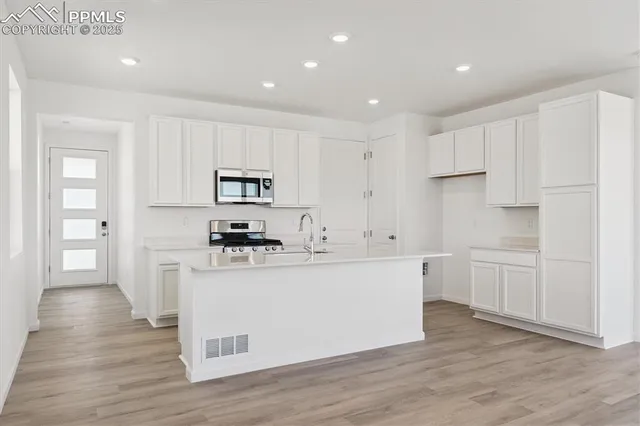 a kitchen with white cabinets and stainless steel appliances