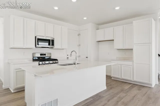 a kitchen with granite countertop a sink stove and white cabinets