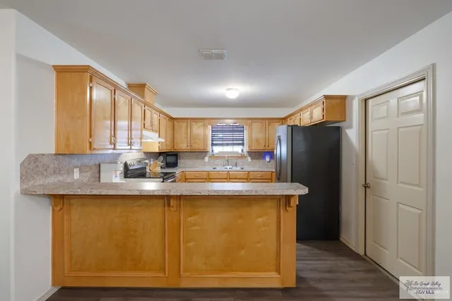 a kitchen with stainless steel appliances granite countertop a refrigerator a sink and a stove