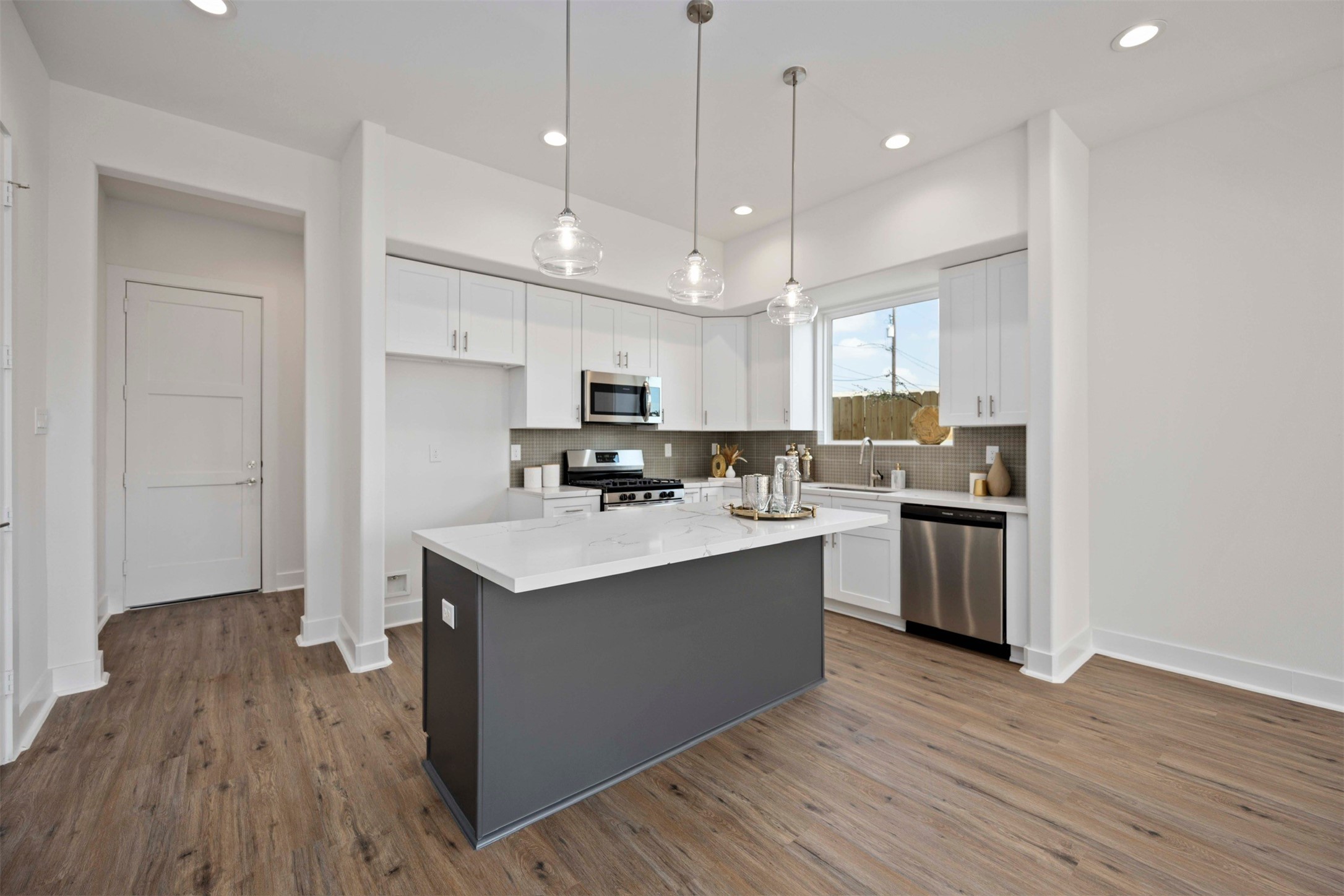 3504 Caplin Street, Unit B Houston, TX 77026 - Photo 4 of 26 a kitchen with kitchen island a sink wooden floor and stainless steel appliances