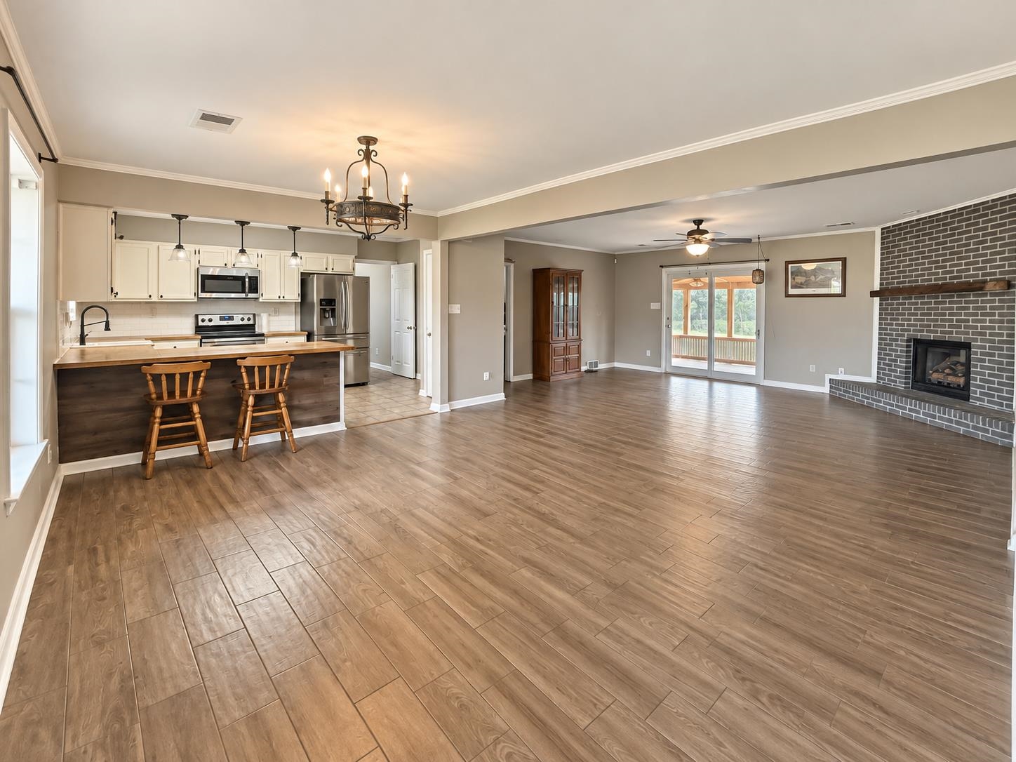 3771 West Union Road Millington, TN 38053 - Photo 4 of 16 Open-concept living space featuring wood-finish flooring, a brick fireplace with a wood mantle, and a kitchen island with a butcher block countertop