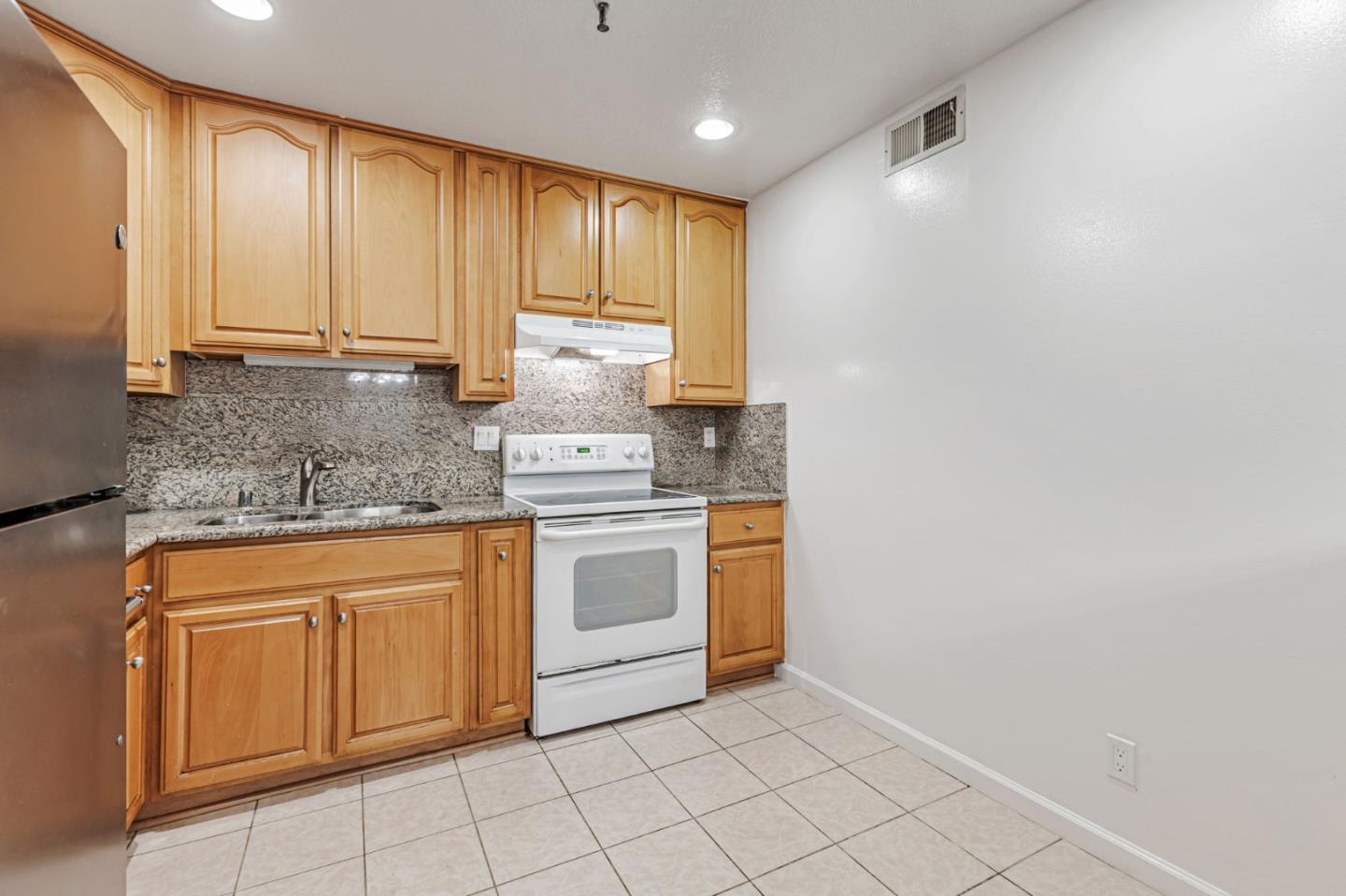 49 Showers Drive, Unit W203 Mountain View, CA 94040 - Photo 20 of 38 a kitchen with granite countertop white cabinets and white appliances