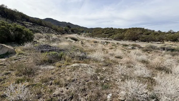 a view of a dry yard with mountains in the background