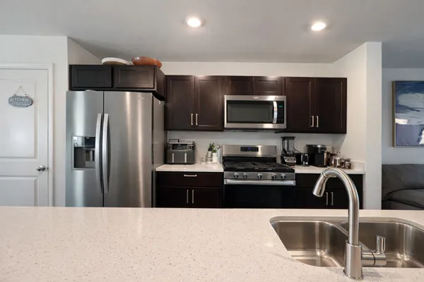 a kitchen with a sink a stove a refrigerator and black cabinets