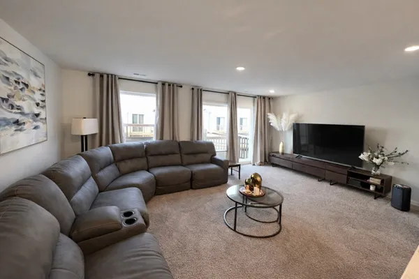 a living room with furniture a flat screen tv and a window