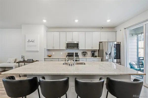a kitchen with stainless steel appliances granite countertop a sink a stove a refrigerator and white cabinets