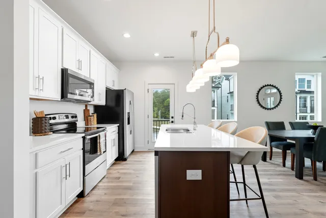 a kitchen with stainless steel appliances kitchen island granite countertop a stove a sink dishwasher a microwave oven a stove with chairs and cabinets