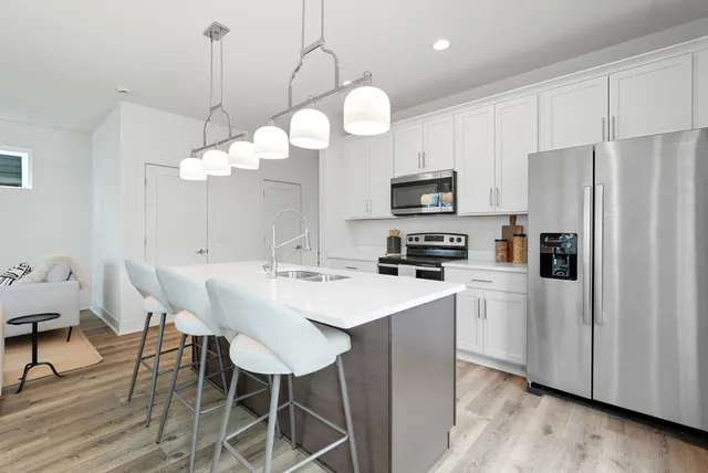 a kitchen with stainless steel appliances a stove a refrigerator a sink a white table and chairs