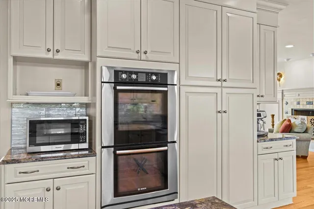 a kitchen with granite countertop stainless steel appliances white cabinets and a window