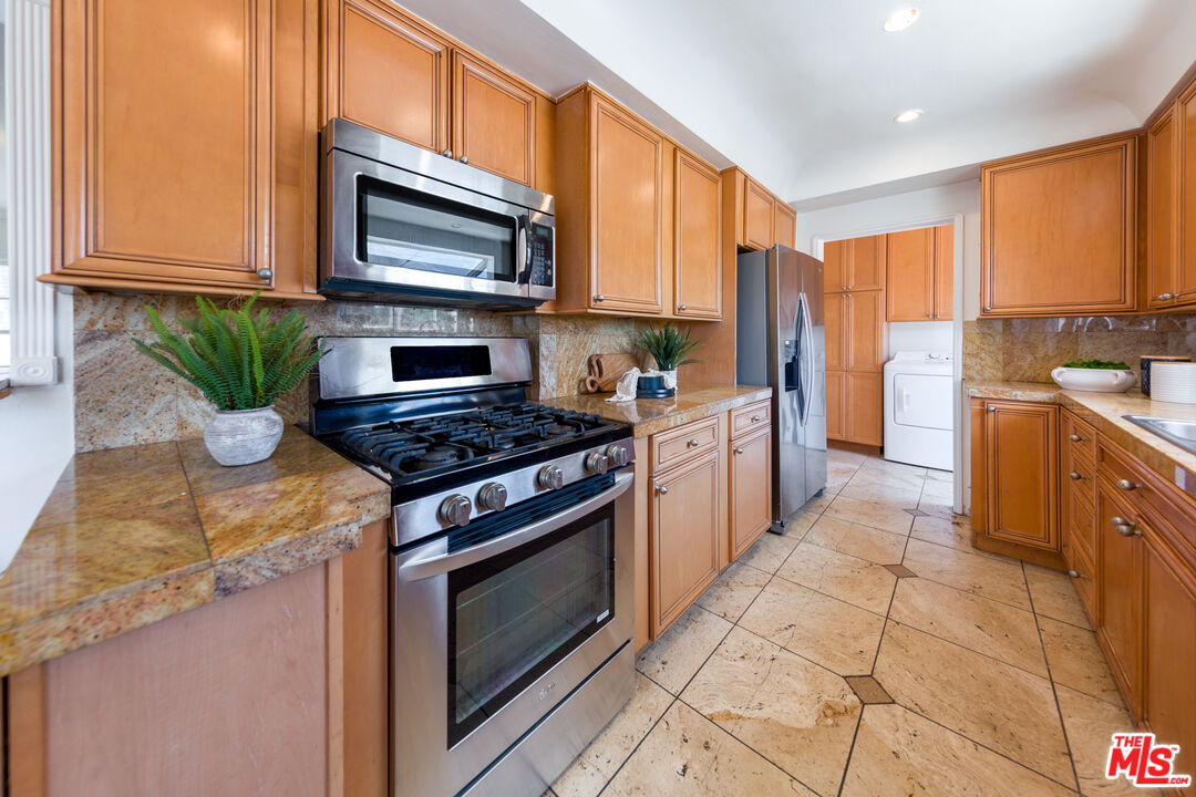 1904 Preuss Road Los Angeles, CA 90034 - Photo 9 of 32 a kitchen with stainless steel appliances a stove a sink cabinets and a microwave