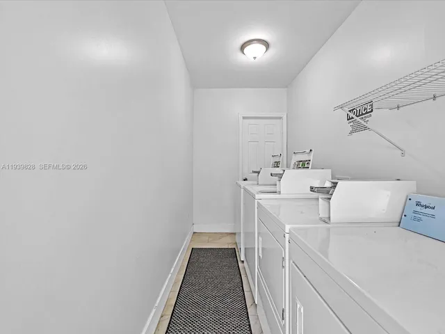 a utility room with a sink a cabinetry and a refrigerator